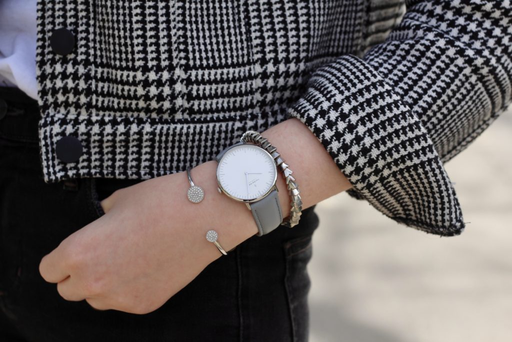 closeup of arm jewelry - two silver bracelets and a minimalistic silver watch from Nordgreen