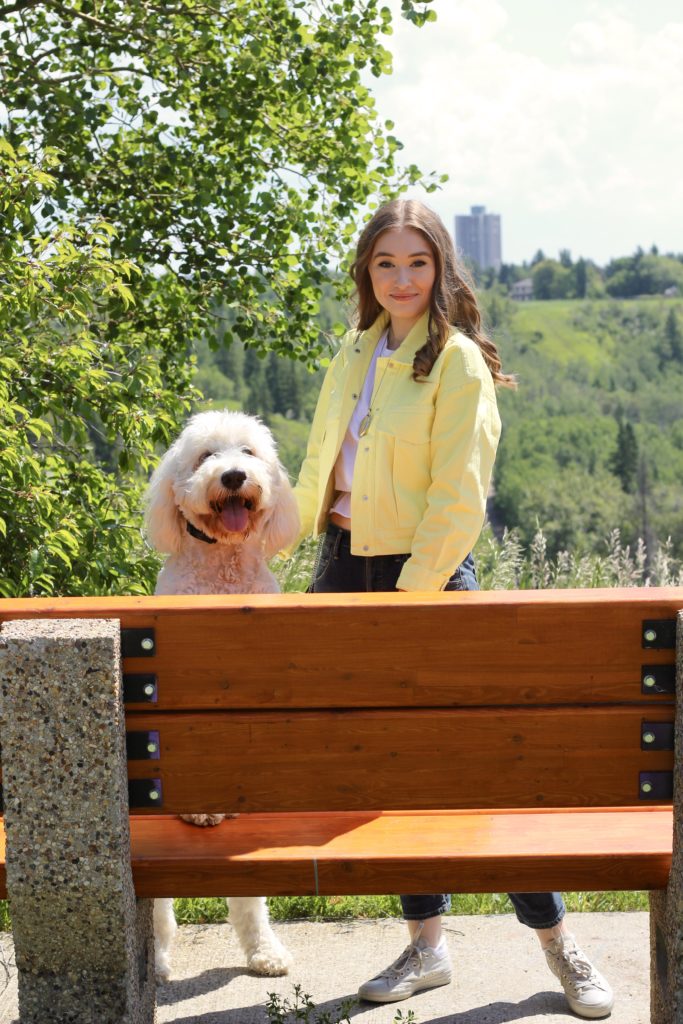 Outfit with yellow denim jacket and embroidered boyfriend jeans, posing with dog, Oakley the Goldendoodle standing on a bench